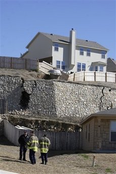 In this Jan. 24, 2010 photo, San Antonio Fire Department personnel survey the damage to a retaining wall as the ground shifts beneath it in San Antonio. (AP Photo/The San Antonio Express-News, Jerry Lara) ** RUMBO DE SAN ANTONIO OUT; NO SALES **