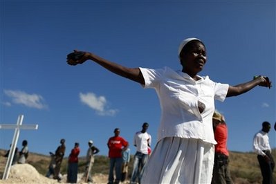 A woman prays during the memorial service for the Haitis earthquake victims that were dumped in a mass grave in Titanyen, outside Port-au-Prince, Monday, Feb. 1, 2010. A 7.0-magnitude earthquake hit Haiti on Jan. 12, killing and injuring thousands. (AP Photo/Rodrigo Abd)