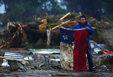 A man holds up a Chilean flag in a flooded area after an earthquake in Pelluhue, some 322 kms, about 200 miles, southwest of Santiago, Sunday, Feb. 28, 2010. A 8.8-magnitude earthquake hit Chile early Saturday. (AP Photo/Roberto Candia)