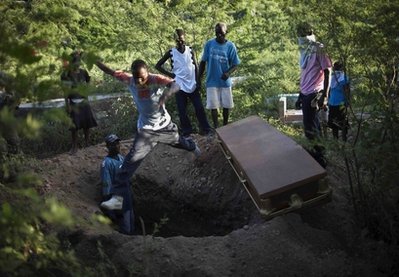 A man jumps over a grave next to the coffin containing the remains of Tikont Dolamard, 36, who died of cholera in Dessalines, Haiti, Sunday, Oct. 24, 2010. A spreading cholera outbreak in rural Haiti threatened to outpace aid groups as they stepped up efforts hoping to keep the disease from reaching the camps of earthquake survivors in Port-au-Prince. Health officials said at least 250 people had died and there are over 3,000 sick. (AP Photo/Ramon Espinosa)