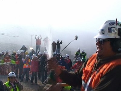 In this still image taken from a video released by Chiles Presidency on Oct. 9, 2010, workers and government officials celebrate with a bottle of champagne as the T-130 drill reaches the 622 meter (2,041 feet) below the surface point after 33 days of drilling to reach the trapped miners on Saturday Oct. 9, 2010, at the San Jose mine near Copiapo, Chile Saturday Oct. 9, 2010. The drilling rig punched through to the underground site where 33 miners have been trapped for 66 days under the Chilean desert, raising cheers, tears and hopes. (AP Photo/Chiles Presidency)