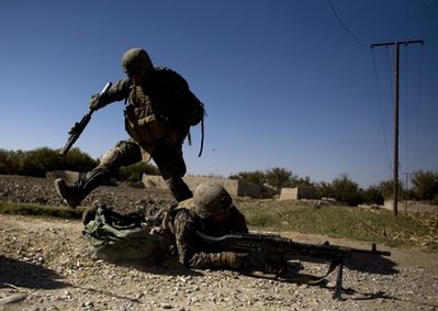 Sgt. Freddia Cavasos, of Visalia, Calif., jumps over Lance Cpl. Andreas Padilla, of Los Angeles, both with India Company, 3rd Battalion 5th Marines, First Marine Division, as shots are fired at their patrol, Sunday, Nov. 7, 2010 in Sangin, Afghanistan. (AP Photo/Dusan Vranic)