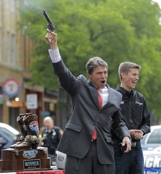 Texas Governor Rick Perry has some fun with a six shooter filled with blanks as NASCAR driver Colin Braun looks on at an event in downtown Fort Worth to kickoff a weekend of NASCAR racing at the Texas Motor Speedway, Thursday, April 15, 2010. (Star-Telegram/Rodger Mallison)