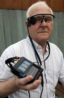 In this photo taken Saturday, Feb. 12, 2011, Eric Selby poses for a photograph with a sight camera fitted in a pair of glasses, as well as its associated computer and transmitter, which work in conjunction with an artificial retina implant called the Argus II fitted in his right eye, enabling him to detect light, in Coventry, England. For two decades, Eric Selby, 68, had been completely blind and dependent on a guide dog to get around. But after having an artificial retina put into his right eye, he can detect ordinary things like the curb and pavement when hes walking outside. (AP Photo/Martin Cleaver)